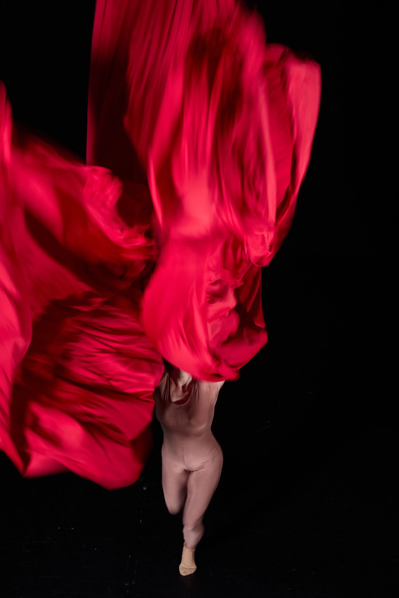 Body disappearing beneath moving red fabric